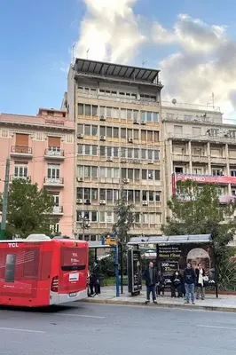 a red bus parked in front of a large building at Panoramic View Athenian Loft in Athens