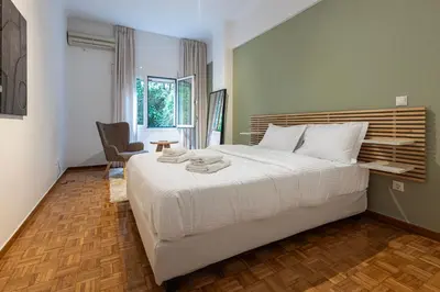 a bedroom with a large white bed and a chair at Lemon Garden Kolonaki Apartment in Athens