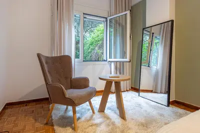 a bedroom with a chair and a table and a window at Lemon Garden Kolonaki Apartment in Athens