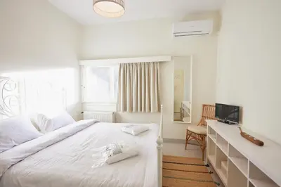 a white bedroom with a bed and a television at Camara Athens Riviera Home in Aghia Marina
