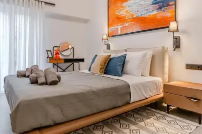 a bedroom with a large bed with a painting on the wall at Elysian Condo, Koukaki in Athens