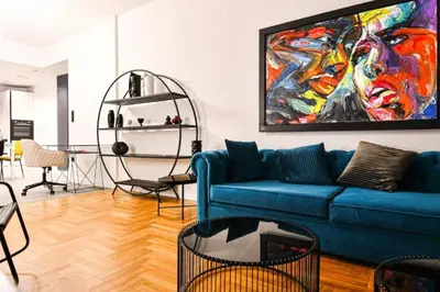 a living room with a blue couch and a painting at Luxury 3br Home at Hip Pangrati in Athens