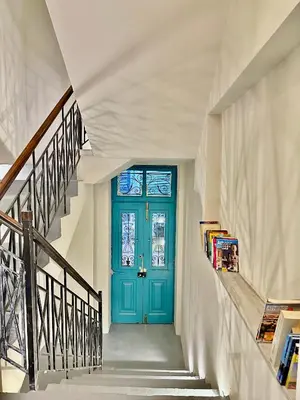a blue door in a white hallway with stairs at Pink Pineapple in Athens