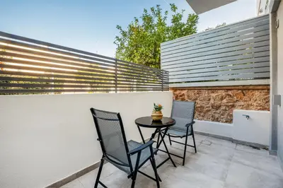 a patio with two chairs and a table on a wall at M&H and their friends A in Athens