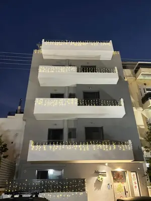 a tall white building with lights on the balconies at M&H and their friends A in Athens