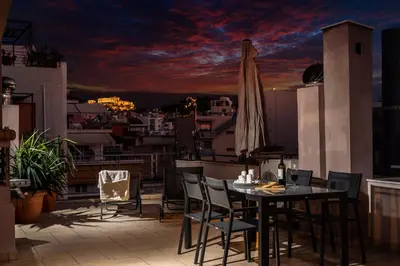 a balcony with a table and chairs and an umbrella at Perfect Stay in Gazi in Athens