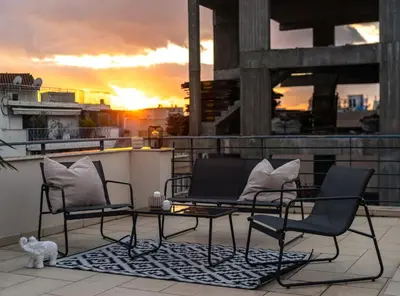 two chairs and a table on a balcony with the sunset at Perfect Stay in Gazi in Athens