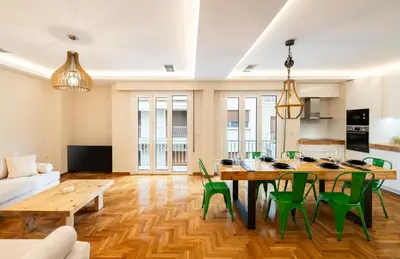 a living room with a wooden table and green chairs at MZ Kolonaki in Athens