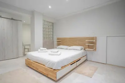 a white bedroom with a large bed with white sheets at Modern apt at Thisio next to the metro station in Athens