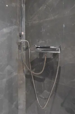 a shower with a hose attached to a wall at Modern apt at Thisio next to the metro station in Athens