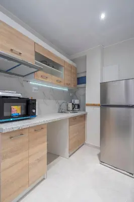 a kitchen with wooden cabinets and a stainless steel refrigerator at Modern apt at Thisio next to the metro station in Athens
