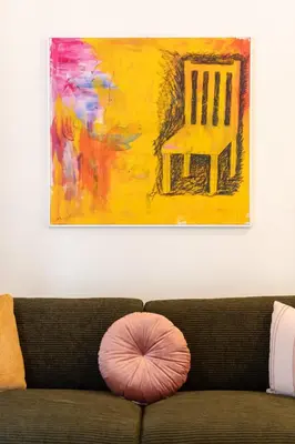 a pillow on a couch in front of a painting at Prime location 1BR Hill Aprtm in Athens