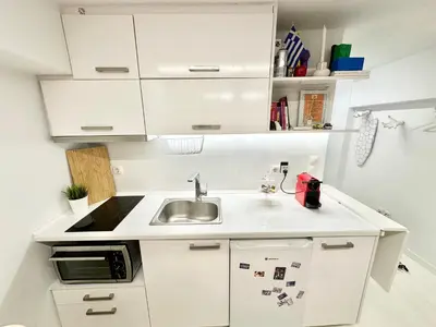 a small kitchen with white cabinets and a sink at Le Petit II Apartment in Athens