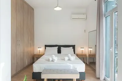 a white bedroom with a large bed and two tables at Neoclassical with Jacuzzi near Acropolis-Living Stone Aragonit in Athens