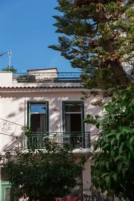 a white building with a balcony and a tree at Neoclassical with Jacuzzi near Acropolis-Living Stone Aragonit in Athens