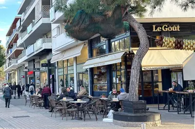 a street with people sitting at tables in front of buildings at Riviera Escape Penthouse Suites in Athens