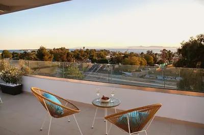 a balcony with a table and chairs and a large window at Riviera Escape Penthouse Suites in Athens