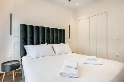 a bedroom with a large white bed with a green headboard at The Emerald of Pagrati in Athens