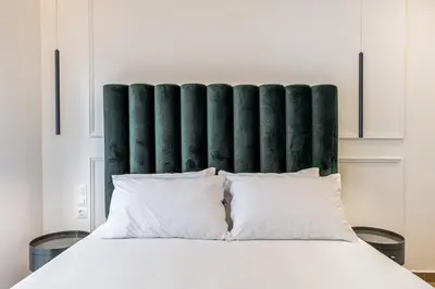 a bed with a green padded headboard and white pillows at The Emerald of Pagrati in Athens