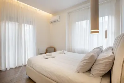 a white bedroom with a large bed with white pillows at The Emerald of Pagrati in Athens