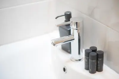 a bathroom sink with a faucet and two bottles at Koukaki Urban Studio in Athens