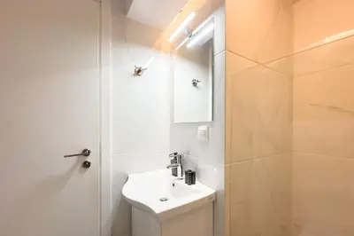 a white bathroom with a sink and a shower at Koukaki Urban Studio in Athens