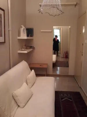 a living room with a white couch and a person in the hallway at super central-metro Acropolis in Athens