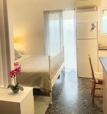 a bedroom with a bed and a kitchen with a refrigerator at lemonsky apartment in Palaiá Fókaia