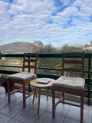two chairs and a table on a balcony at lemonsky apartment in Palaiá Fókaia