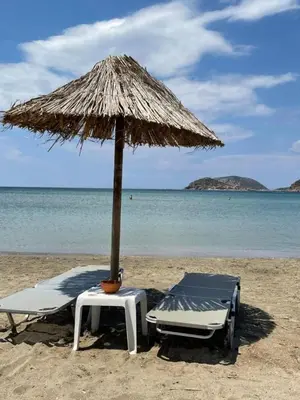 a chair and an umbrella on a beach at lemonsky apartment in Palaiá Fókaia
