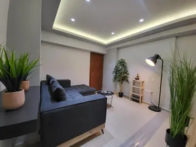 a living room with a blue couch and some plants at Glory Apartment 3is septemvriou in Athens