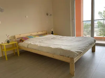 a wooden bed in a bedroom with a yellow table at Argithea View in Papangeláki
