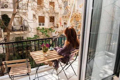 a woman sitting at a table on a balcony at Kolonaki Prime Location Luxurius Flat in Athens