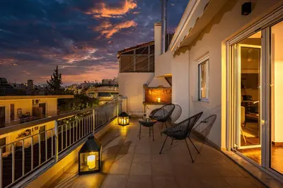 a balcony with chairs and a table with lights at Penthouse in Koukaki with Acropolis view in Athens