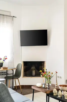 a living room with a fireplace with a tv above it at Penthouse in Koukaki with Acropolis view in Athens
