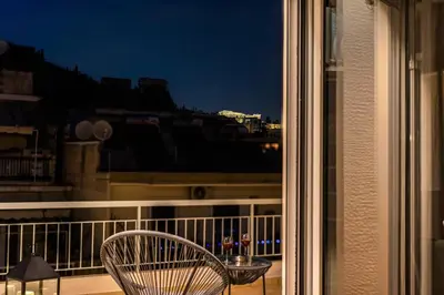 a chair sitting on a balcony looking out a window at Penthouse in Koukaki with Acropolis view in Athens
