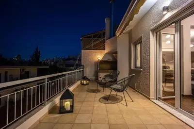 a balcony with two chairs and a table at night at Penthouse in Koukaki with Acropolis view in Athens