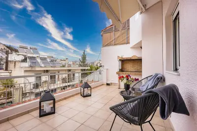 a balcony with two chairs and a fireplace on a building at Penthouse in Koukaki with Acropolis view in Athens