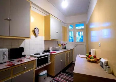 a kitchen with yellow cabinets and a table with a bowl of fruit at Spacious Apartment 2 minutes from Omonoia Metro in Athens