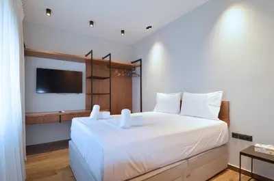 a bedroom with a large white bed with a flat screen tv at Modern two bedroom apartment Stili Olympioy Dios in Athens