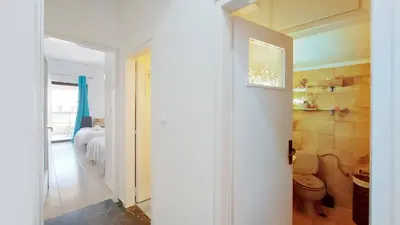 a hallway leading to a bedroom with a bed and a bathroom at Cholargos a Spacious 2BR apartment with great view in Athens