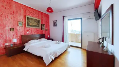 a bedroom with a white bed and a red wall at Cholargos a Spacious 2BR apartment with great view in Athens