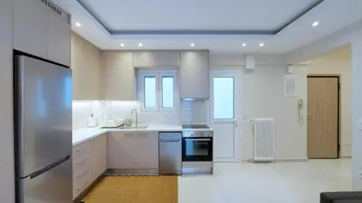 a large white kitchen with a stainless steel refrigerator at A modern and bright apartment in Kolonaki in Athens