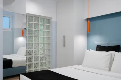 a bedroom with two beds and a partition with glass at Acropolis Secret Apartment in Athens