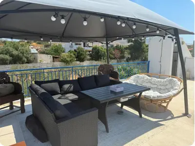 a patio with a couch and a table under an umbrella at Aegean Home in Áyios Nikólaos
