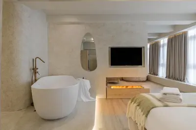 a hotel room with a tub and a tv at Minimalist Oasis in Athens in Athens