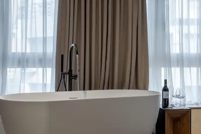 a white bath tub in a bathroom with windows at Urban Serenity Suite in Athens in Athens