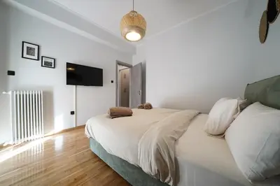 a white bedroom with a bed and a flat screen tv at New Delightful Apartment in Athens