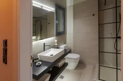 a bathroom with a sink and a toilet and a mirror at Phaedrus Living Athens Metsovou Residence in Athens