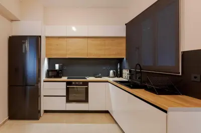 a kitchen with white cabinets and a black refrigerator at Phaedrus Living Athens Metsovou Residence in Athens